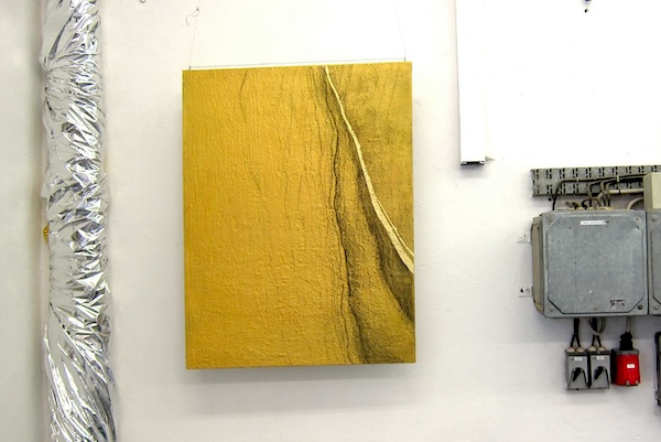 Gold, painting with sand and gold leaf, exhibition view, hanging next to a pipe covered in aluminium foil and a fuse box